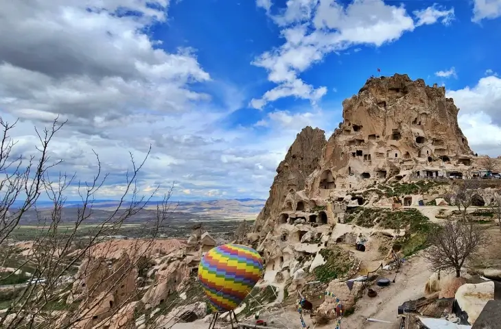 Uçhisar Kalesi ve Kapadokya vadilerinin panoramik manzarası, ön planda dekoratif balon objesi